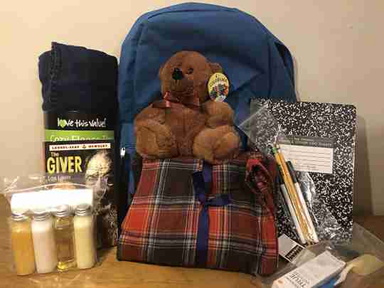 Brown bear in a backpack with a lot of supplies.