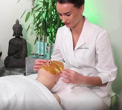 Christine Valmy expert esthetician applying a gold collagen professional care mask during a spa facial treatment