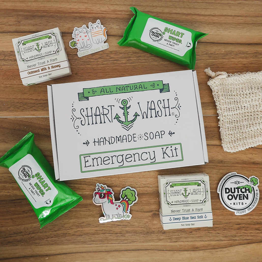 picture of shart wash emergency kit gift box sitting on a wood ackground. 2 bars of shart wash soap, 2 packs of shart wipes and a soap bag