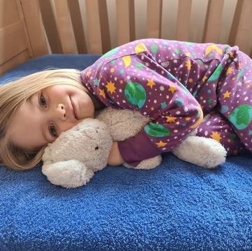 little girl laying down on bed in onesie