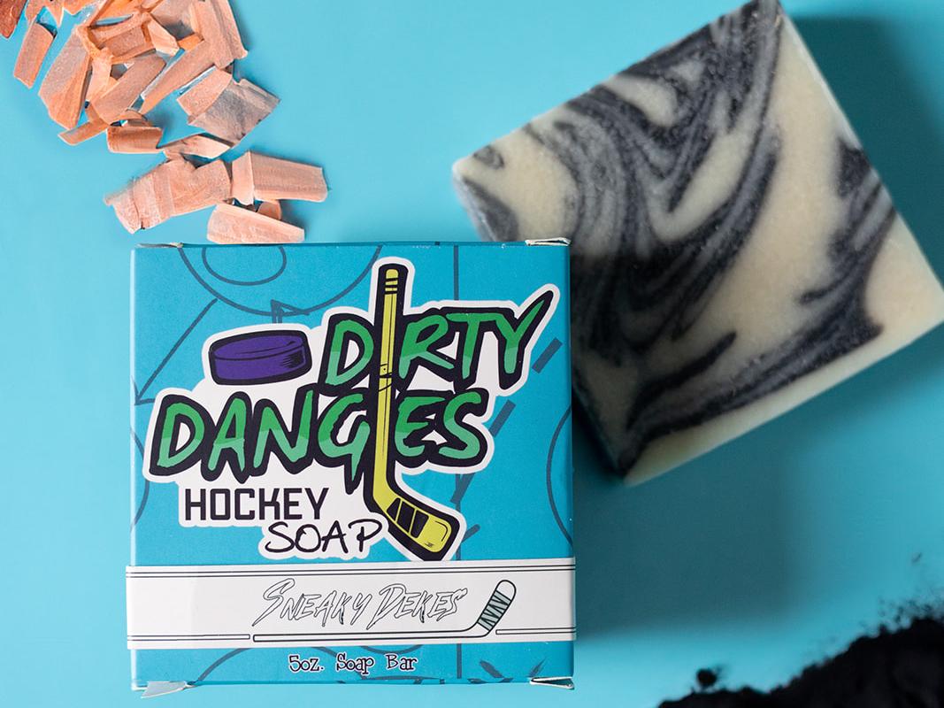 sneaky dekes black and white swirl hockey soap bar and box on a blue background with sandalwood and charcoal