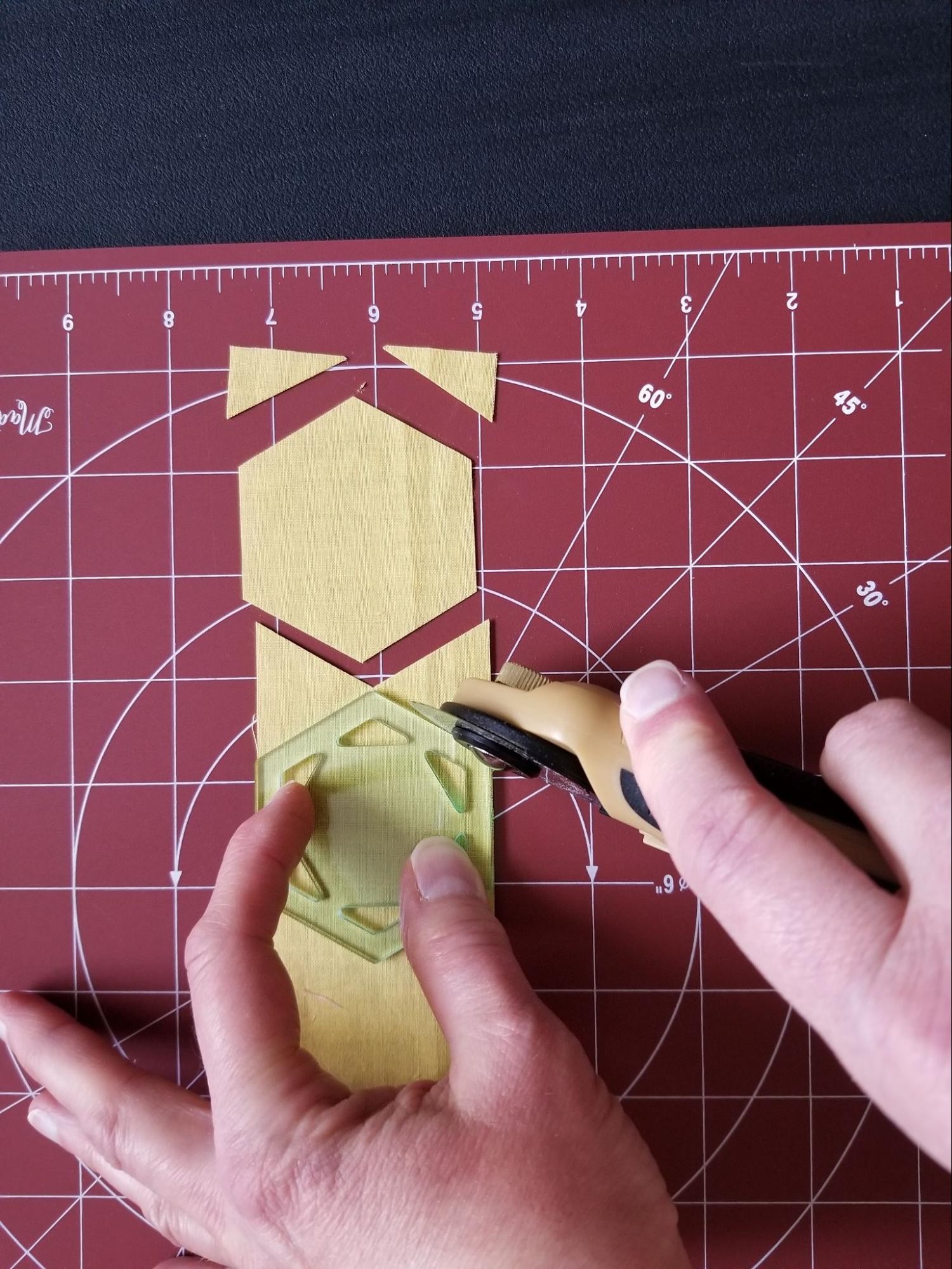 Aligning and cutting the second hexagon when using a fabric strip and hexagon quilt template.