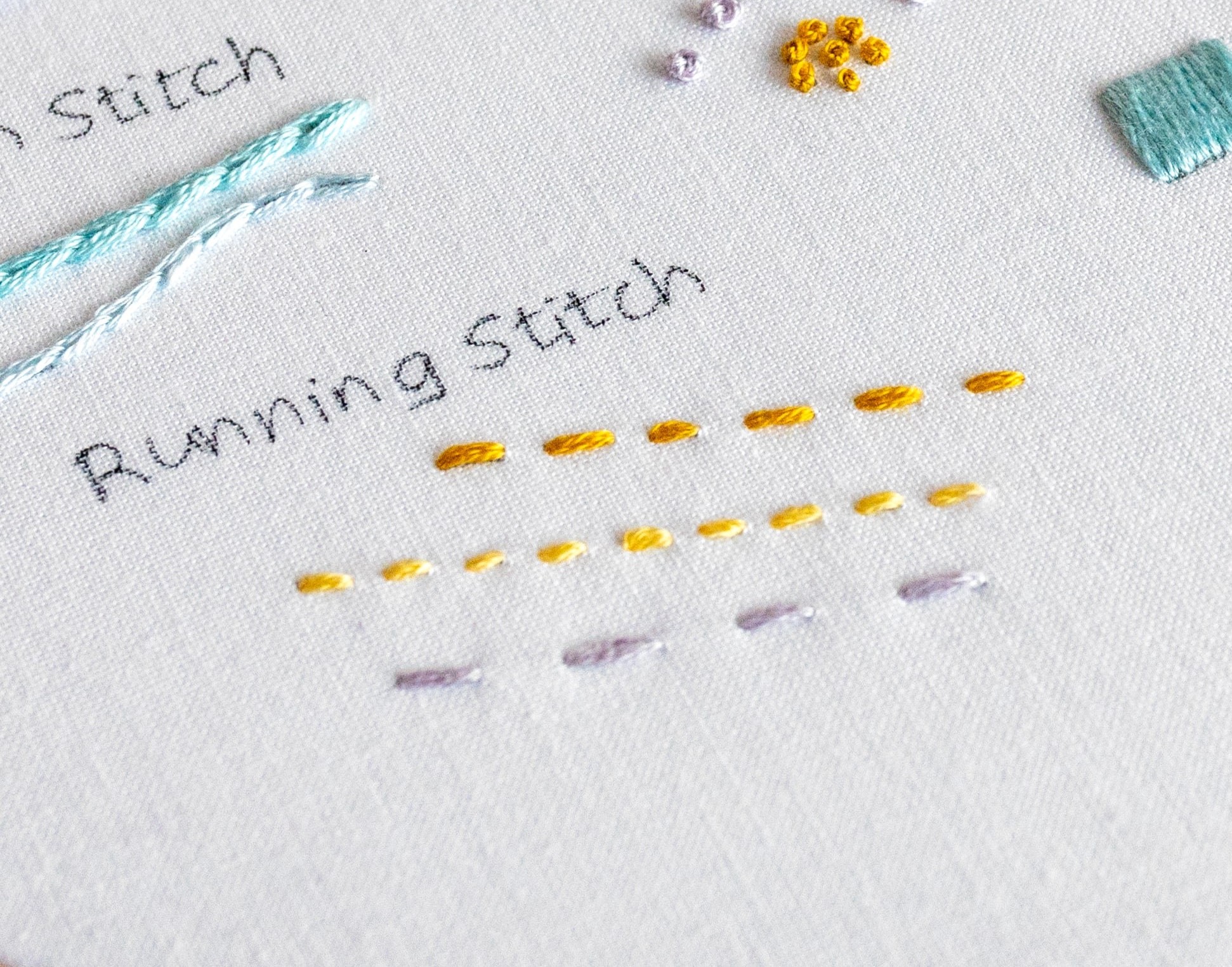 Multiple embroidery stitches are stitched on a fabric background.