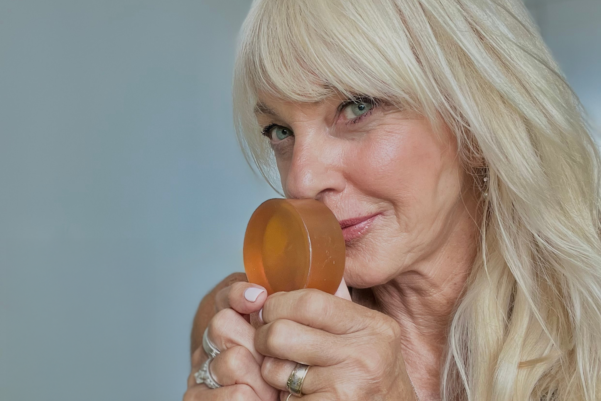 Woman holding Mirai Clinical deodorizing soap bar with persimmon, effective for reducing body odor and nonenal.