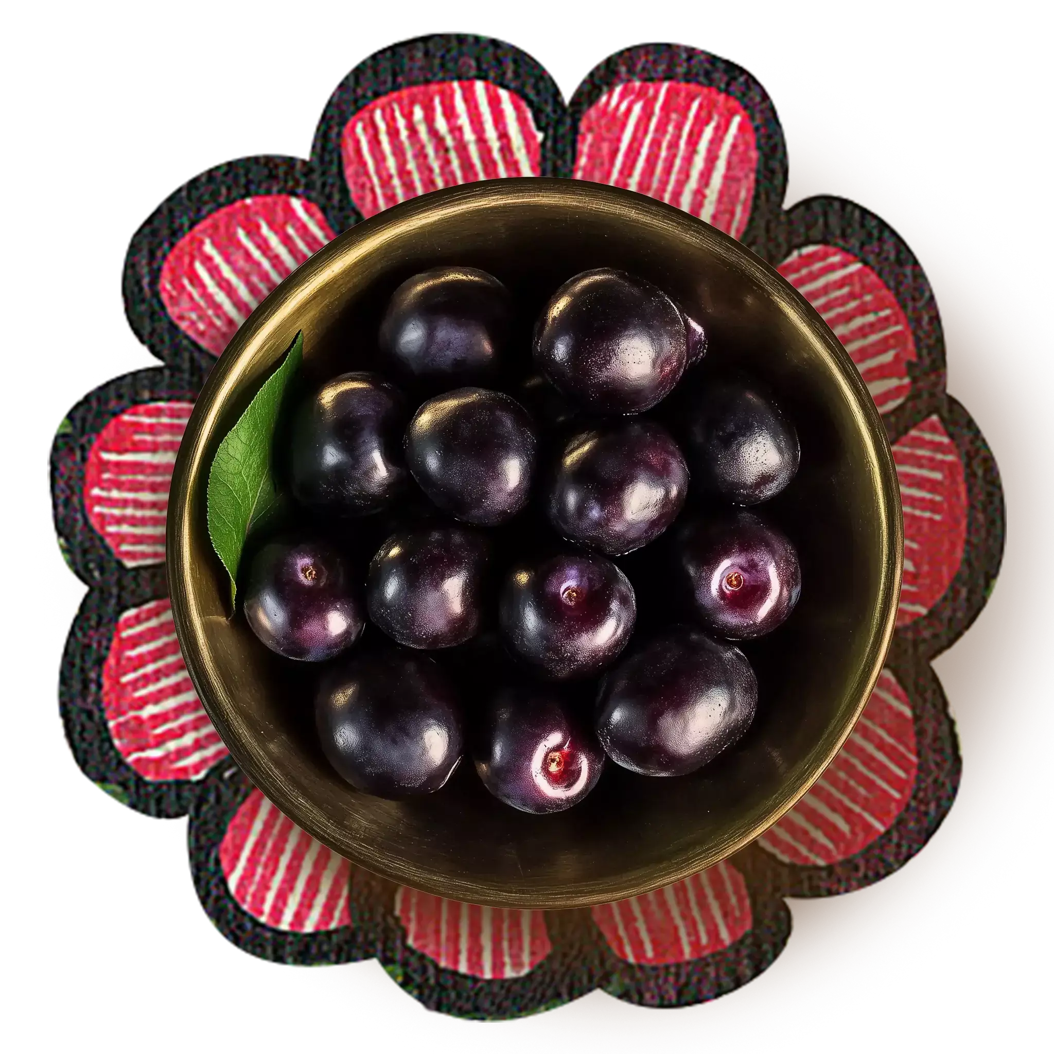 Black plums kept in a brass bowl over an artwork of a pink flower