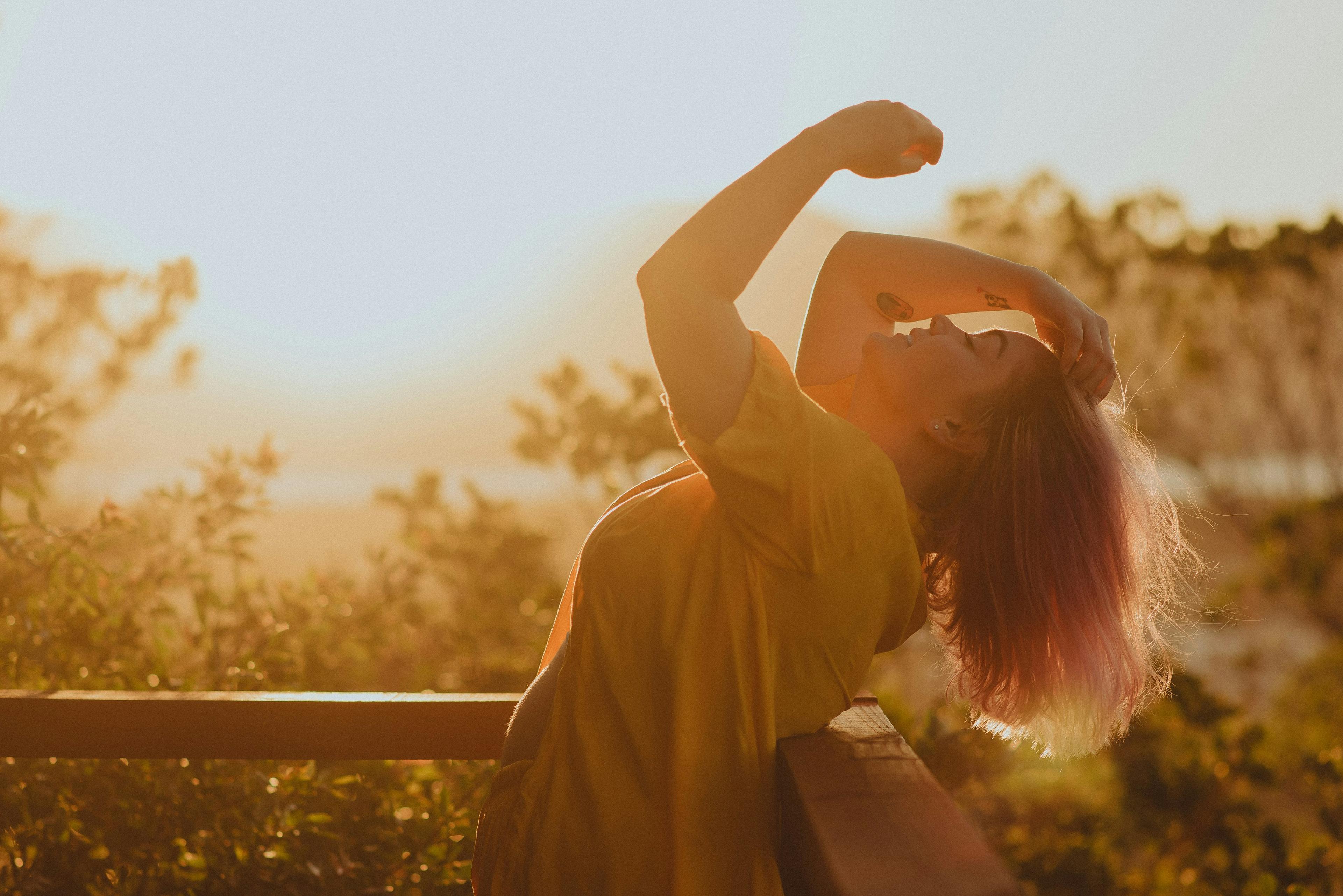 Woman shaking her hair out in the early morning sun to soak up Vitamin D to support her fertility.