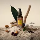 A bottle of prinourish serum, with ingredients, like, almond, black pepper, black plum, ginger and more, kept on a rock