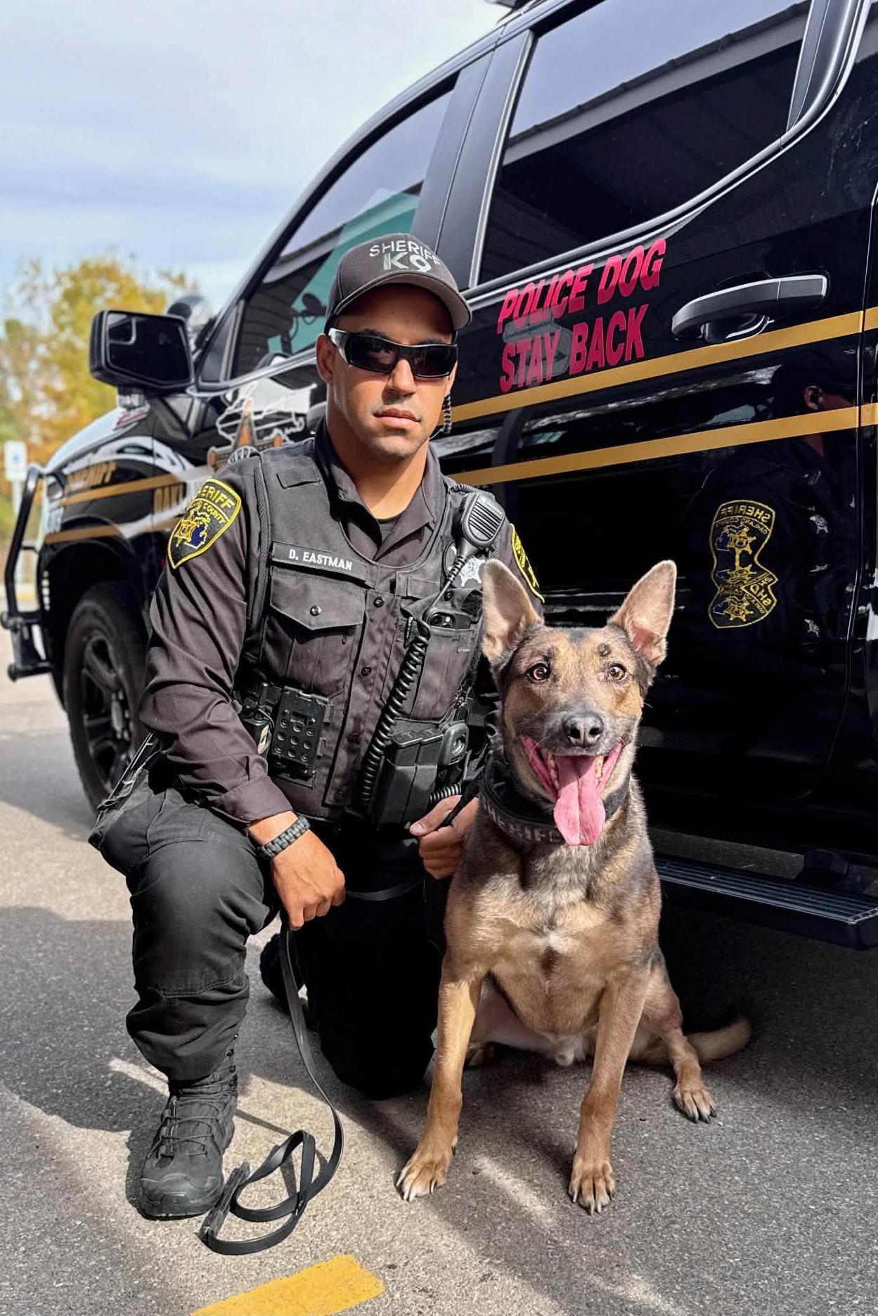 k9 bleu with his handler and a police vehicle