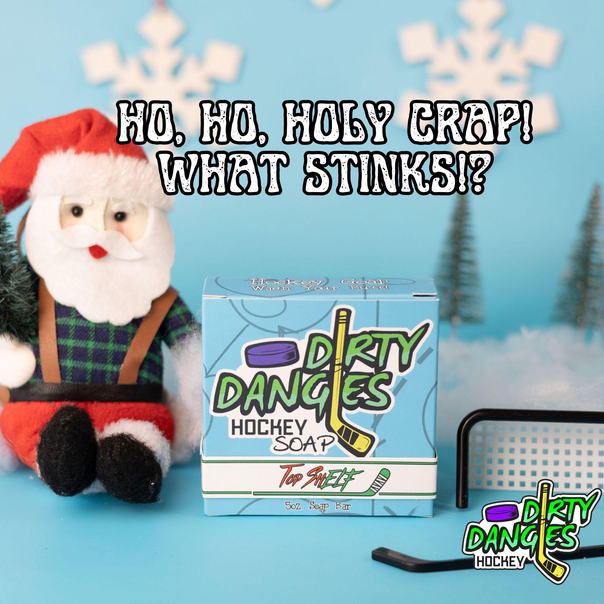 Ho Ho Holy crap! What stinks?! A bar of dirty dangles Top Shelf soap on a blue Christmas background with a stuffed Santa Claus and a tiny hockey goal, puck and stick.