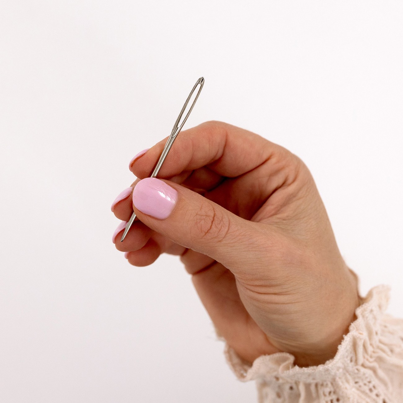 A hand holds a weaving needle.