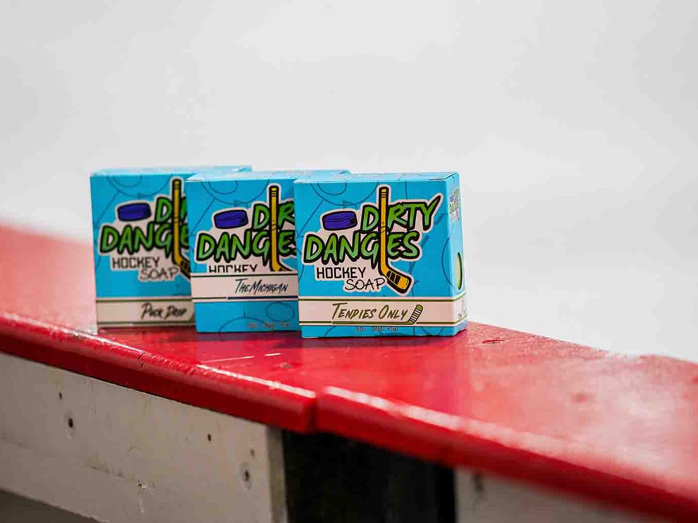 3 hockey soap bars on the boards of an ice rink. Puck drop, the michigan and tendies only scents.