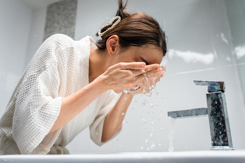 Woman washing her face as the first step in her skincare routine.