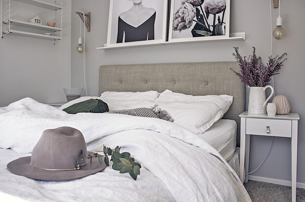 A grey headboard is on a bed with beautiful decor around the room.