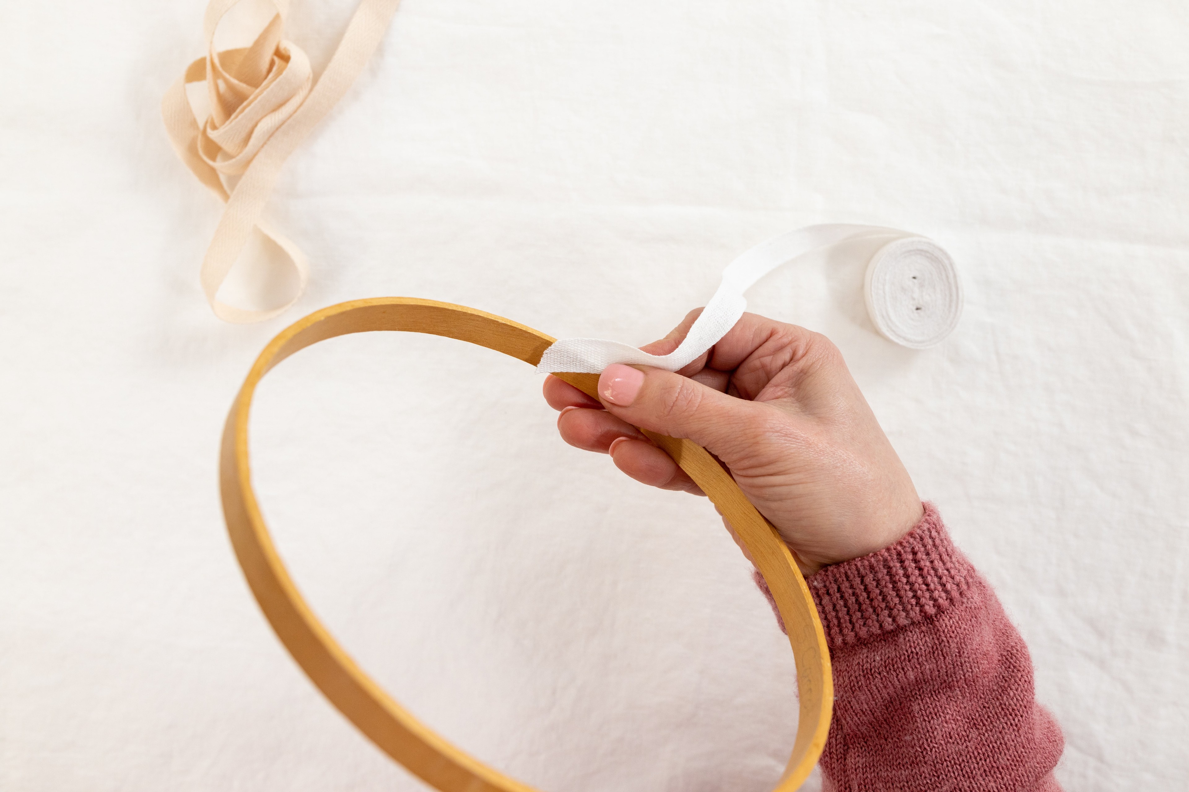 A hand holds tape on a hoop.