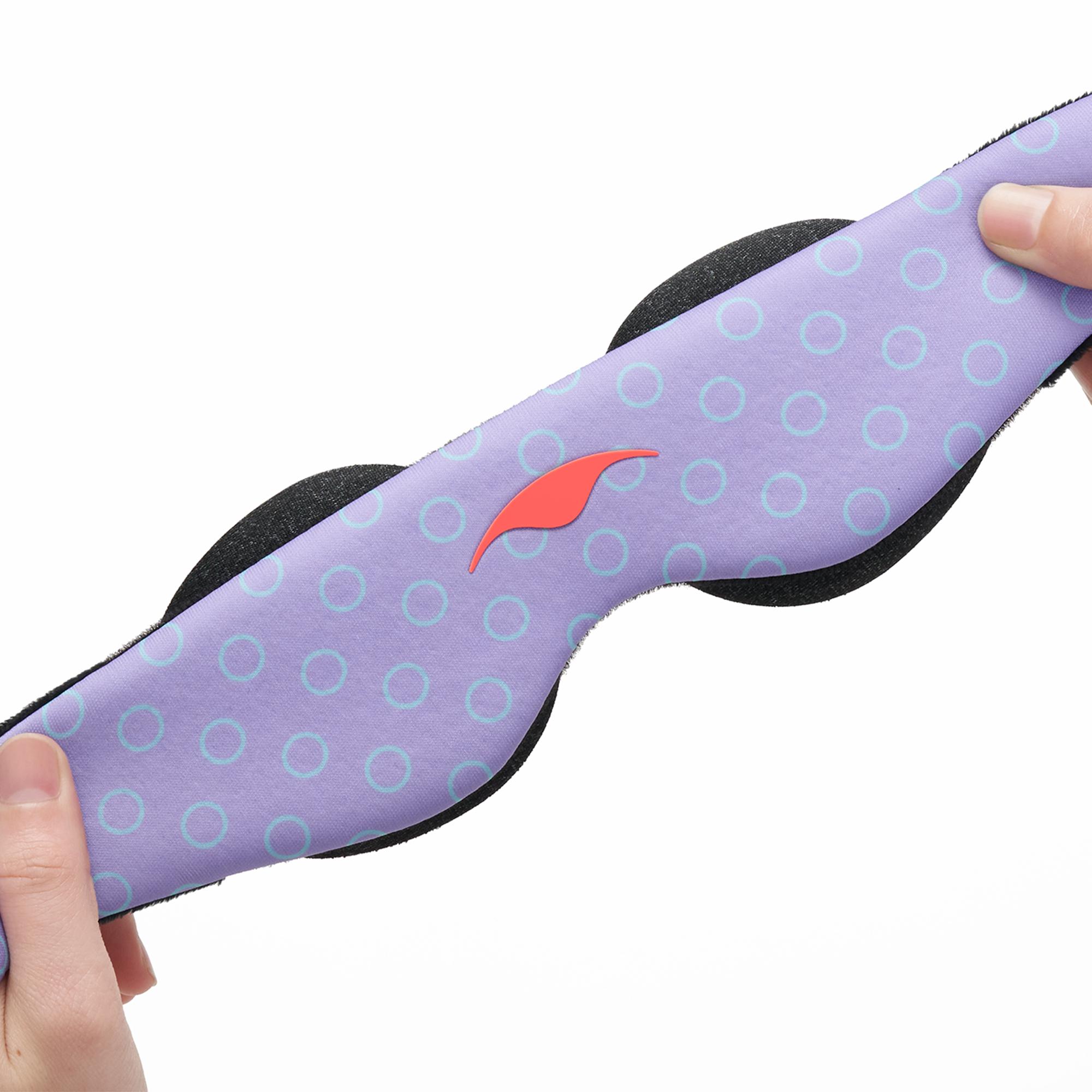 Hands holding a girls' sleeping mask with a purple and blue circles design.