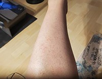 Customer's leg with visible skin texture and a healthy sheen, indicative of the nourishing effects of Bella Terra Oils, set against a kitchen countertop backdrop.