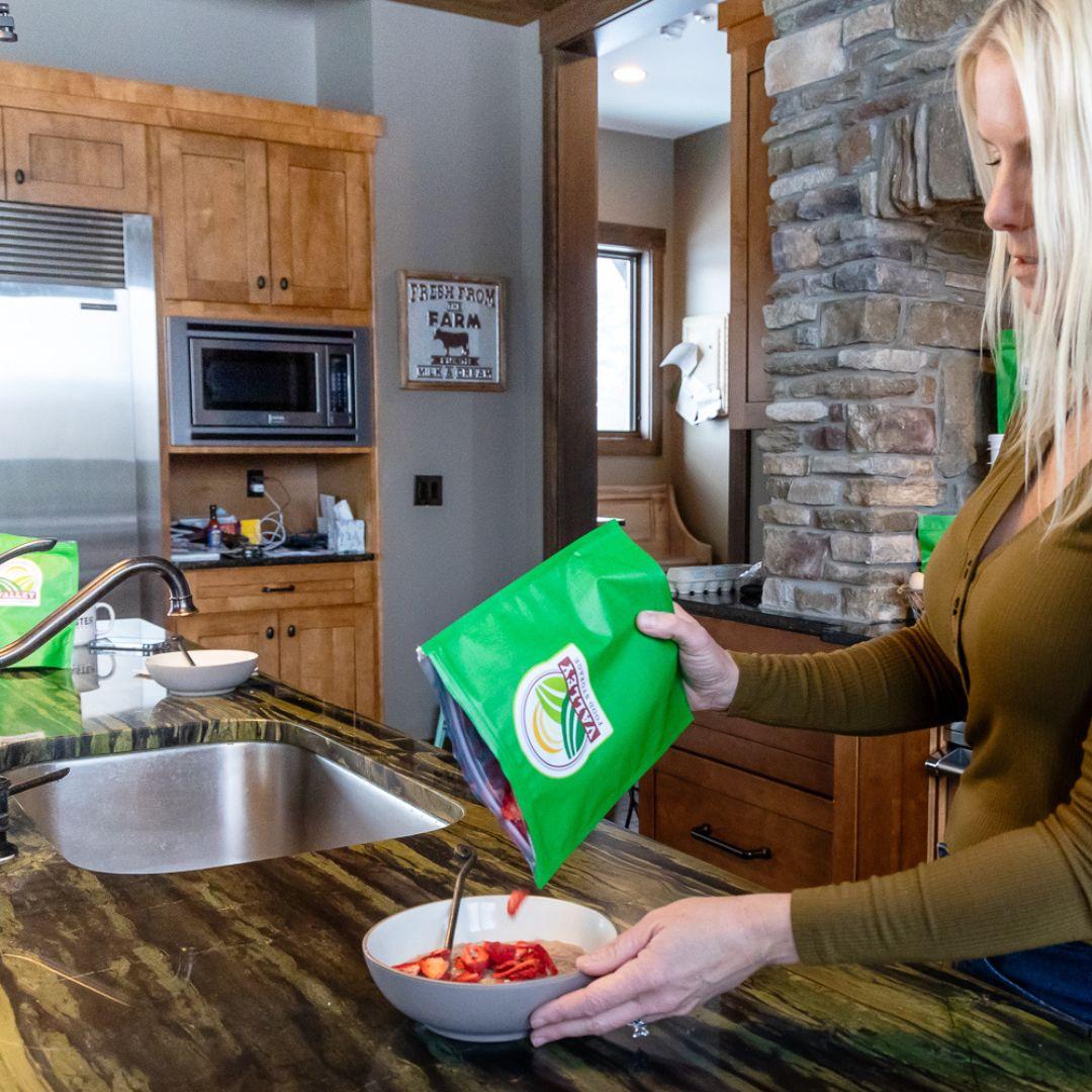 Woman preparing Valley Food Storage meal in kitchen, stirring contents from green package into bowl