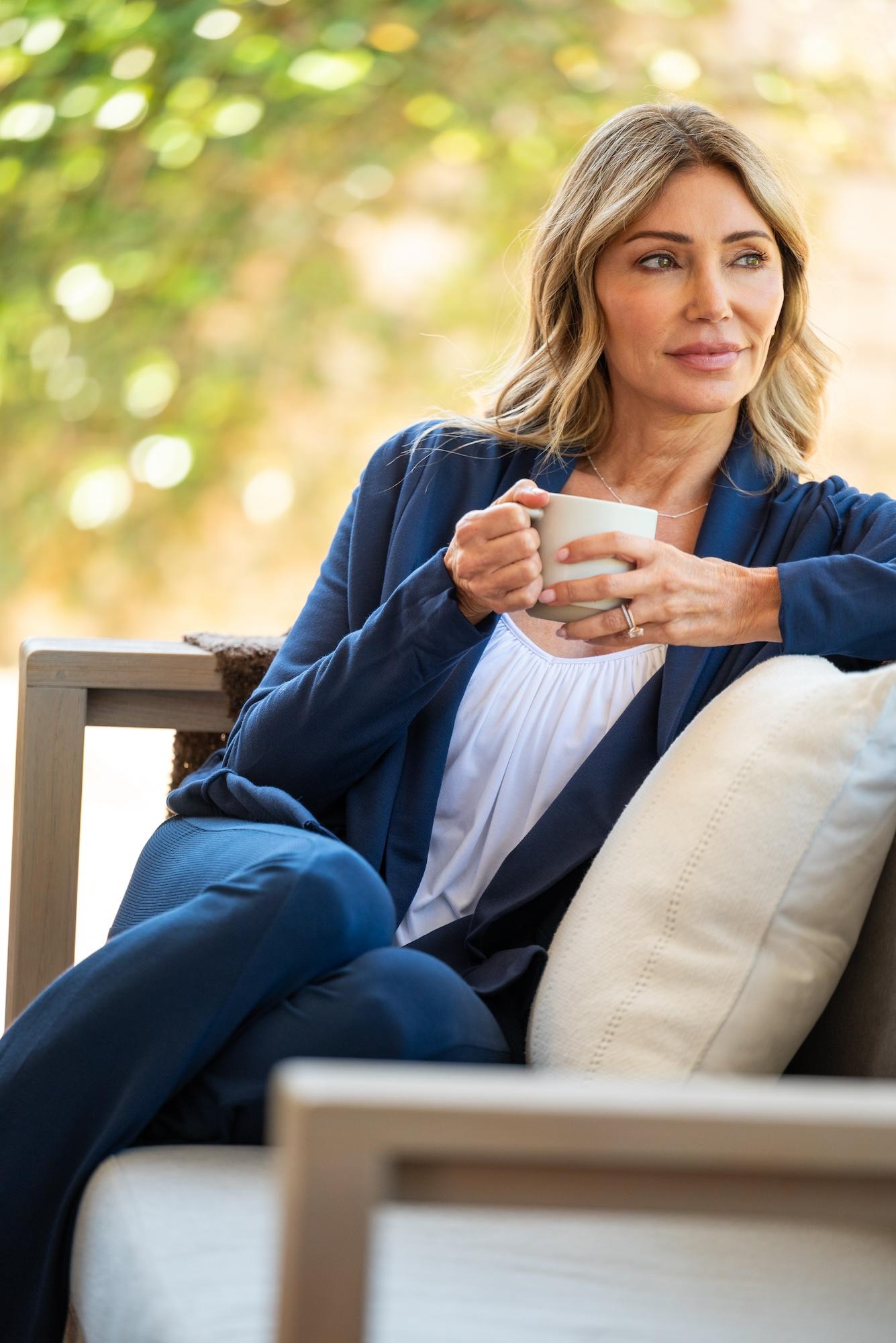 Woman wearing JJwinks lounging on an outdoor couch with coffee