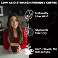 Woman holding a cup of coffee with icons showing low acidity, stomach-friendly benefits, and smooth flavor — Lone Wolf Coffee