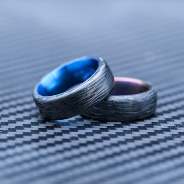 The Hyper Core Carbon Fiber Ring is an anodized titanium ring that can be made with a blue or purple liner
