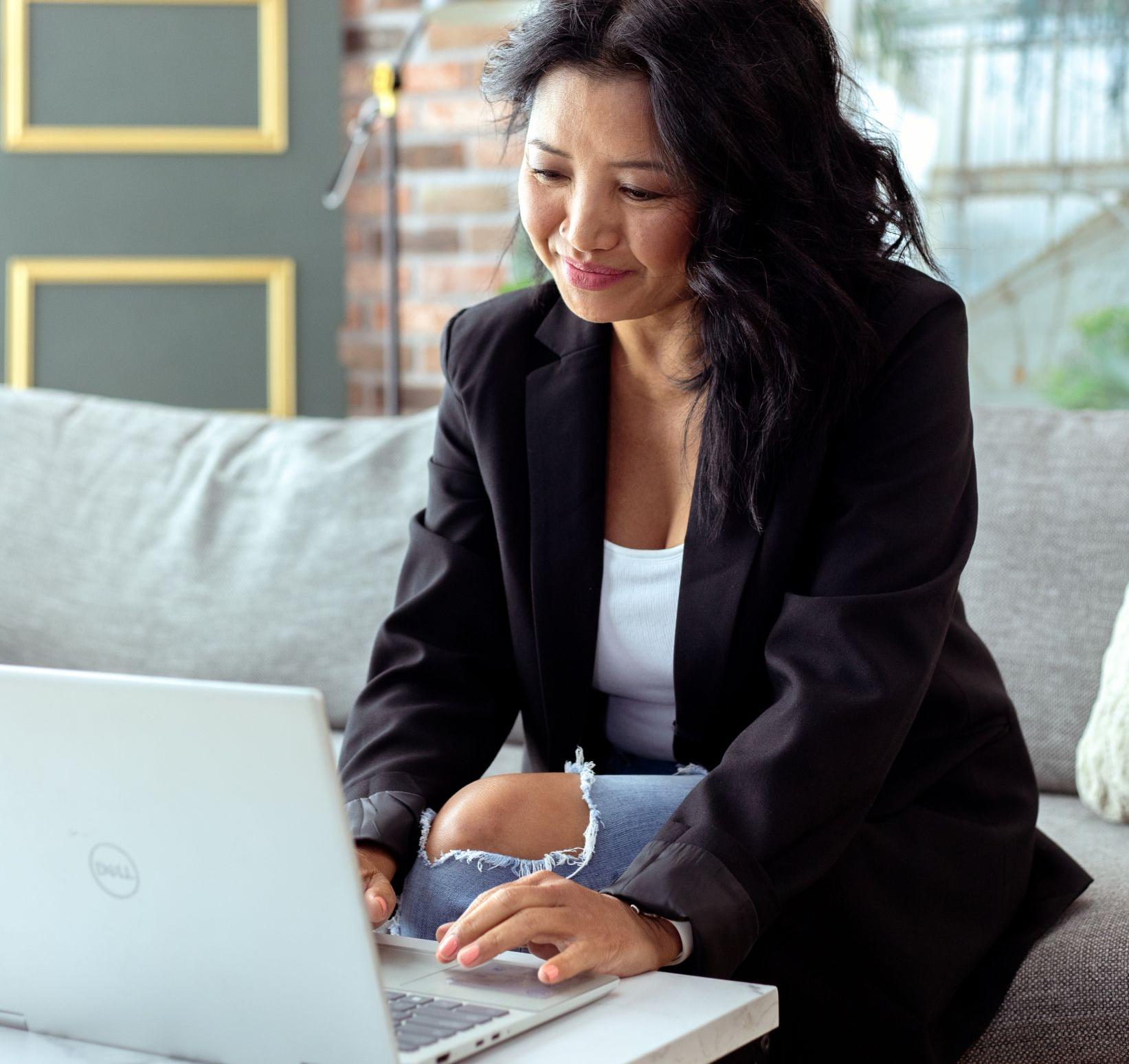 Tina Somsith working on her laptop helping struggling clients get clarity