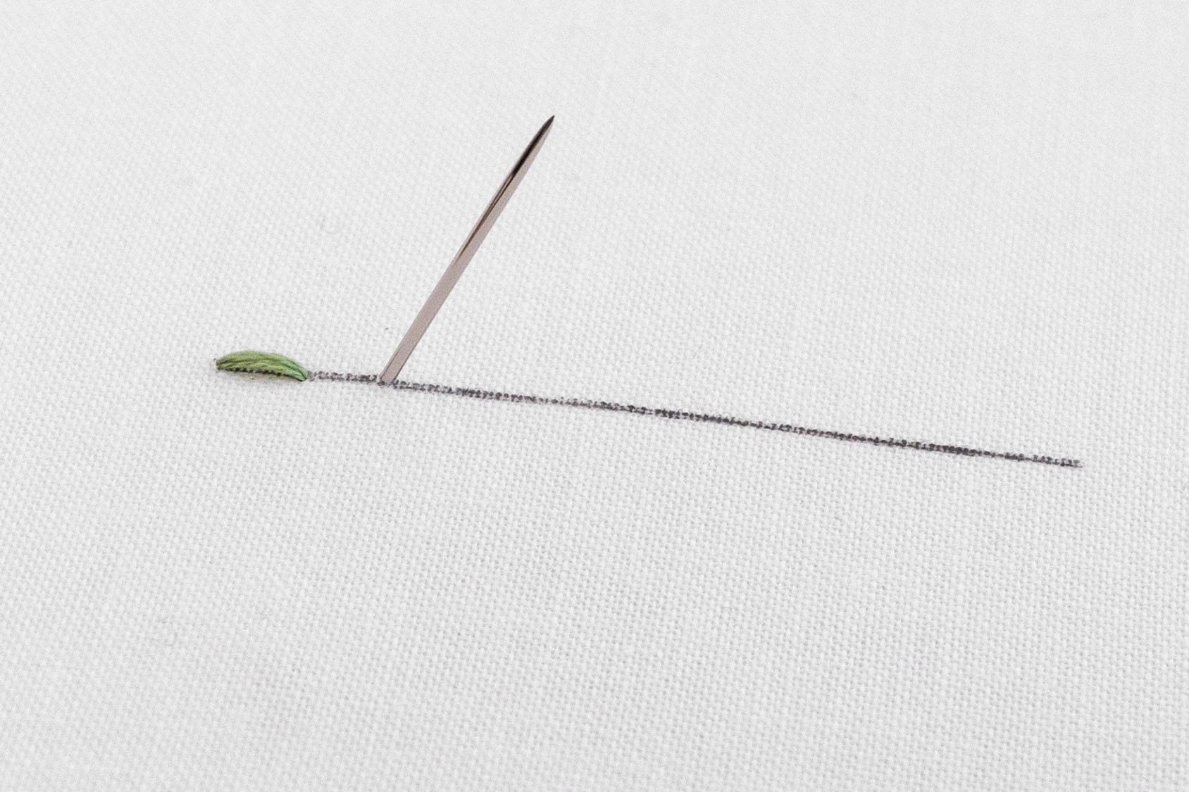 The needle is poked through the back of the embroidery fabric.