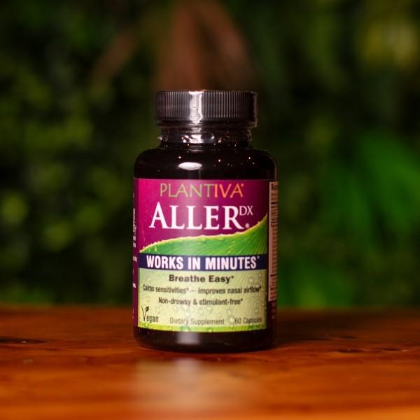 A bottle of AllerDx on a wooden counter with greenery in the background