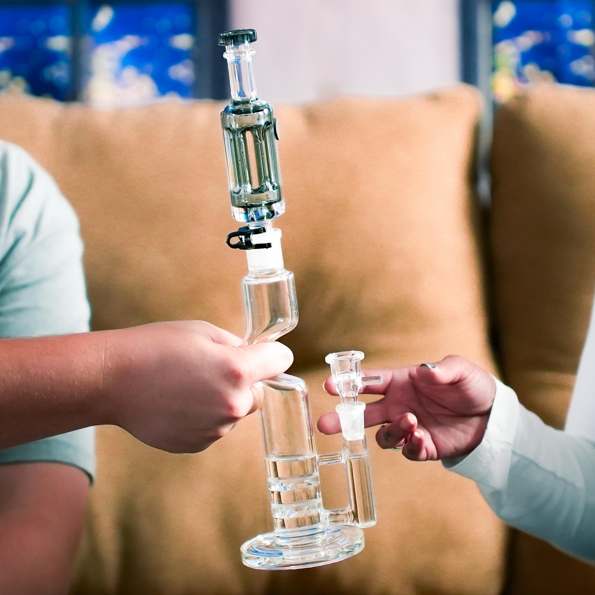 hands passing glass recycler bong