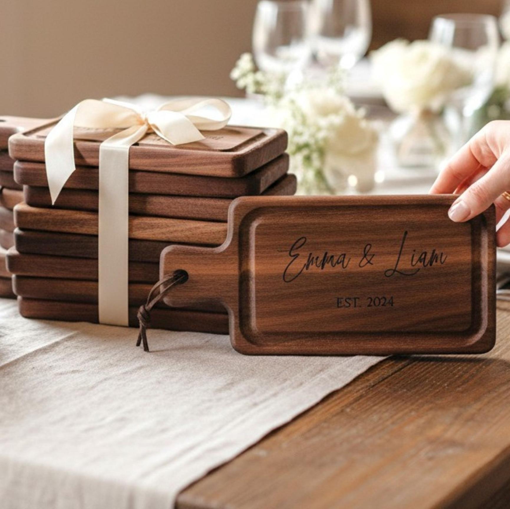 Personalized walnut mini charcuterie board with wedding engraving stacked with gift ready boards and ribbon packaging