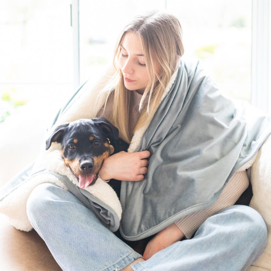 Dog and owner snuggling in the Potty Buddy blanket