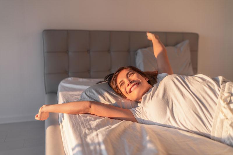 A lady happily waking up with the sun