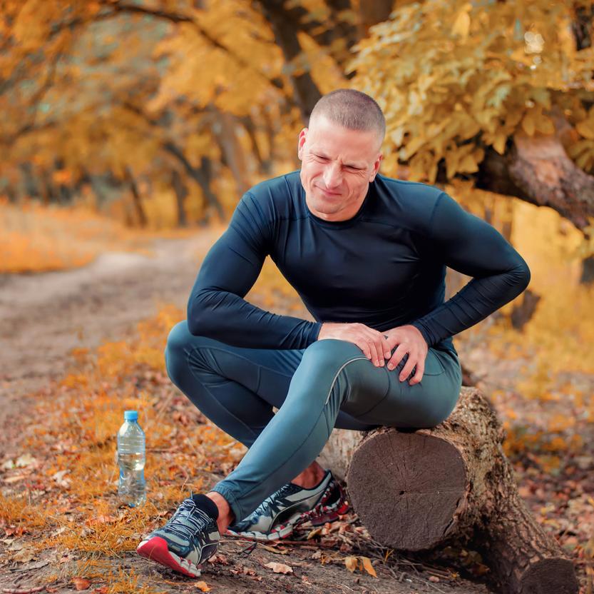 A young athletic jogger feels a strong pain in the muscle after cramping