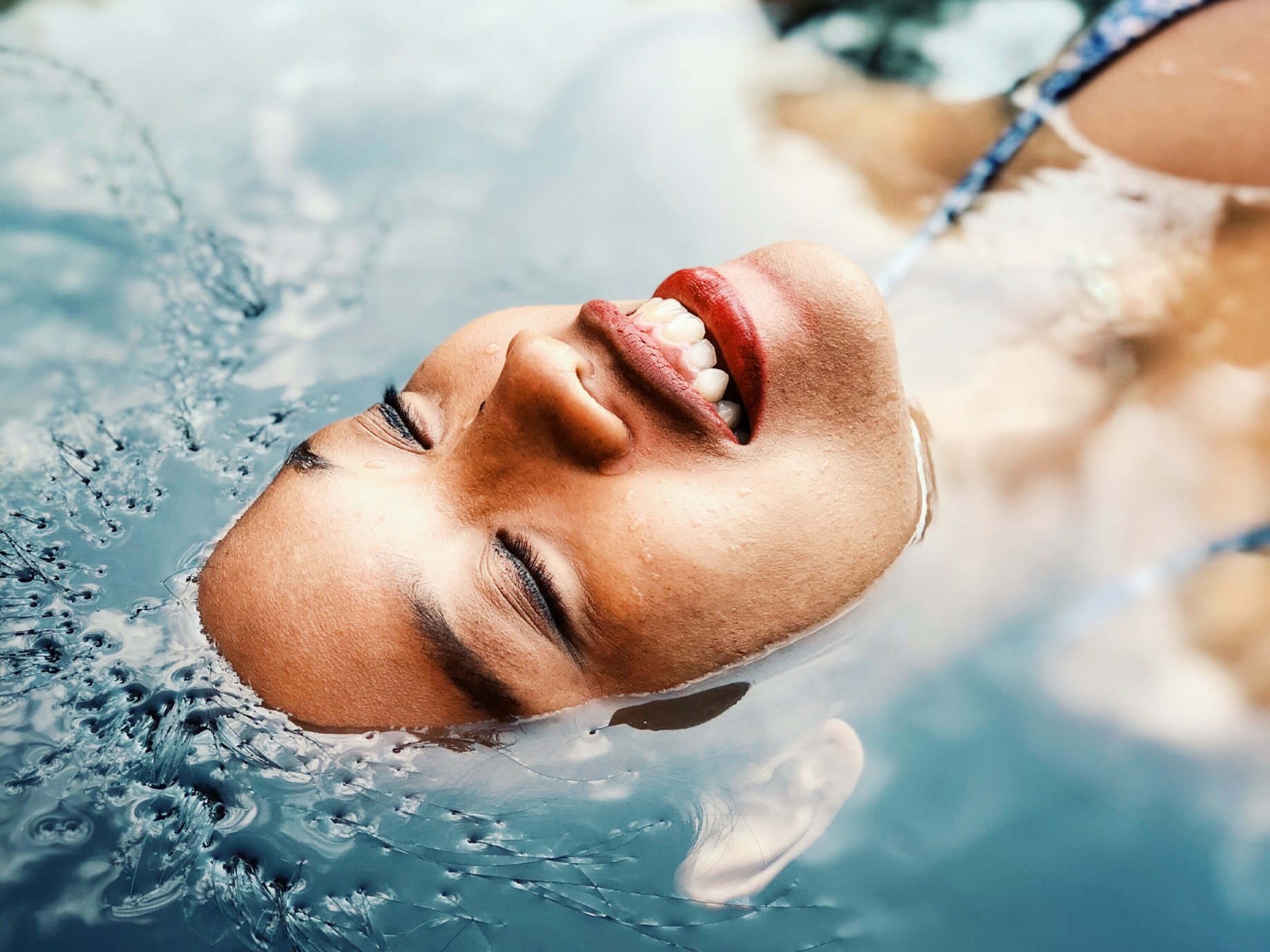 black woman with natural hair submerged in water while swimming in a back float