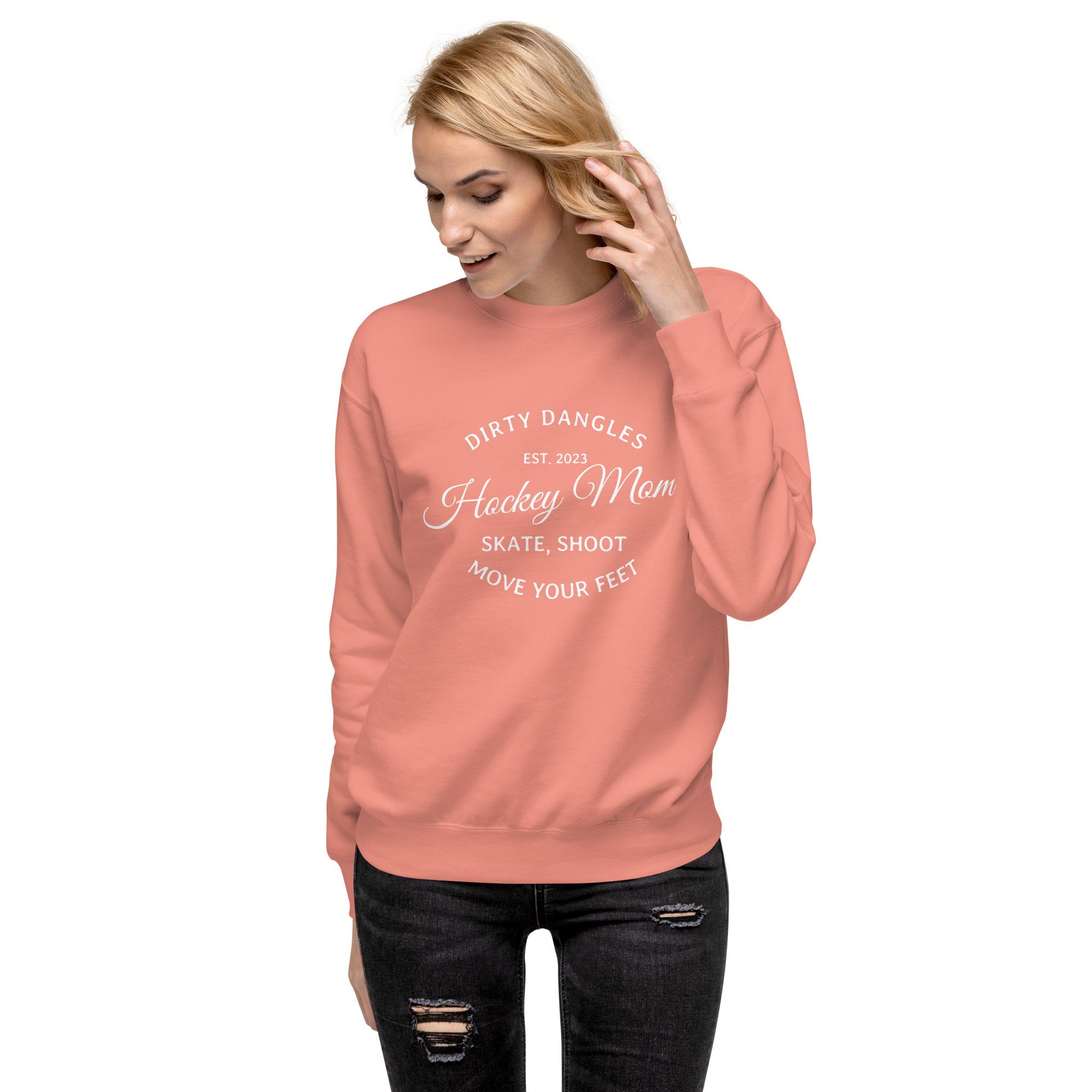 A hocky mom wearing a pink dirty dangles hockey mom crew neck sweatshirt on a white background