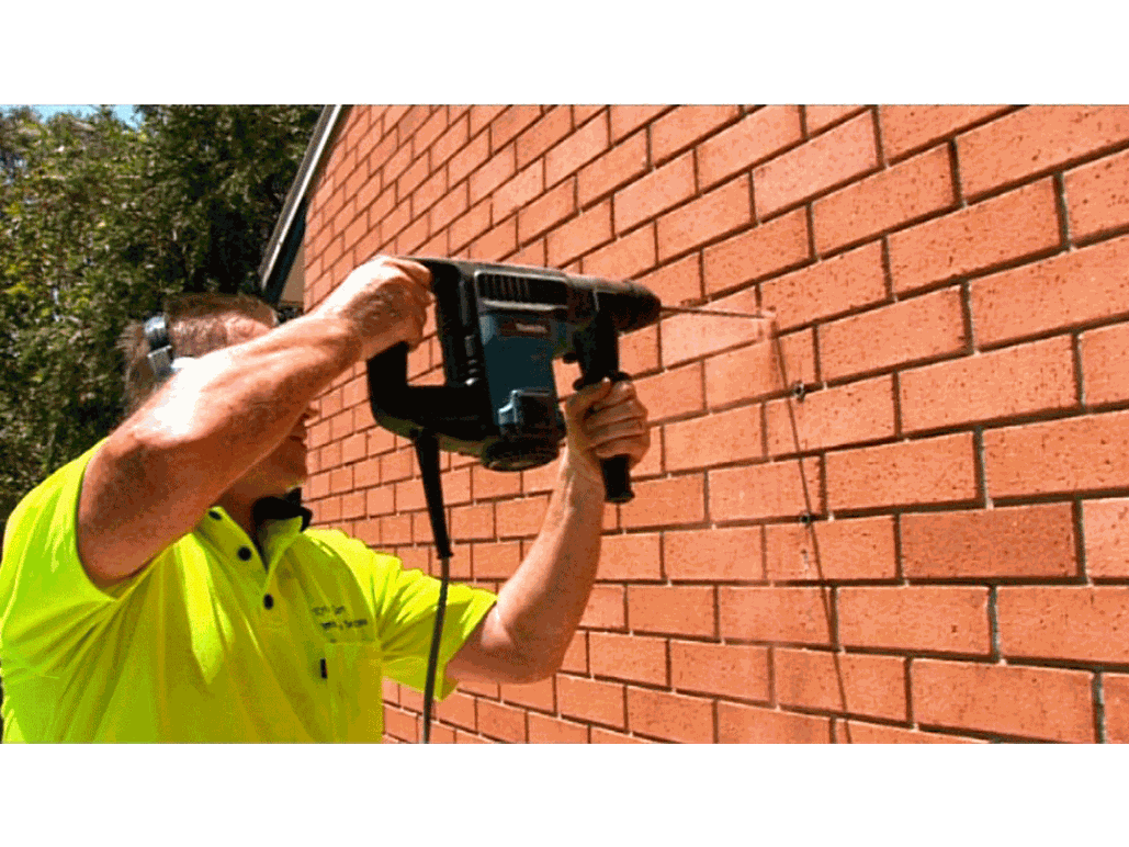 clothesline installation and supply with installer drilling into brick wall to mount clothesline