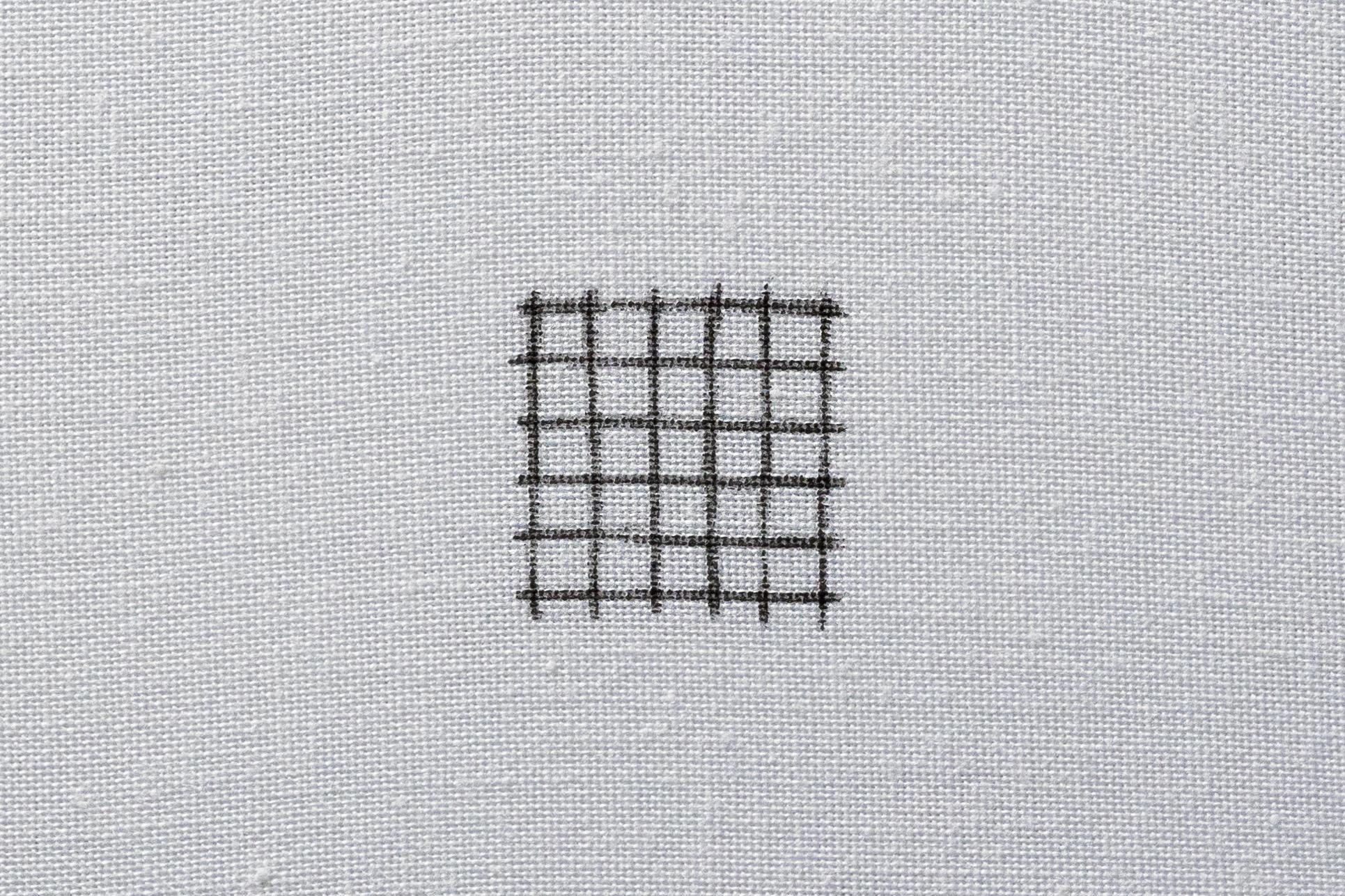 Evenly spaced directional lines drawn onto fabric, forming a grid.