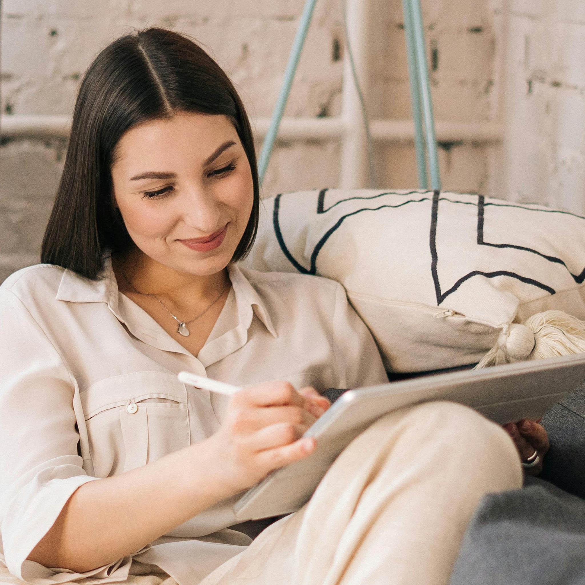Woman using iPad on sofa for digital bullet journaling in GoodNotes