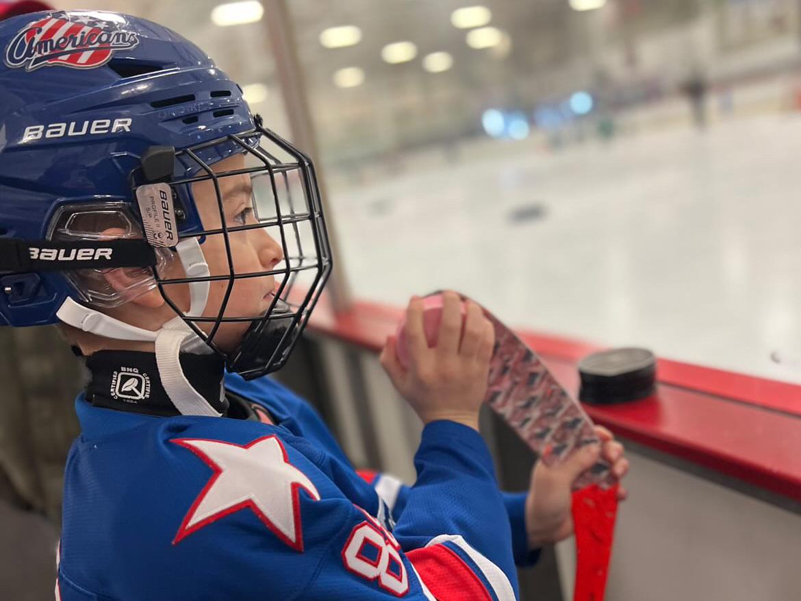 a youth hockey player applying dirty dangles hockey stick wax to a taped blade