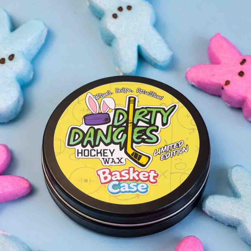 A yellow tin of dirty dangles basket case marshmallow scented stick wax on a blue background with easter candy