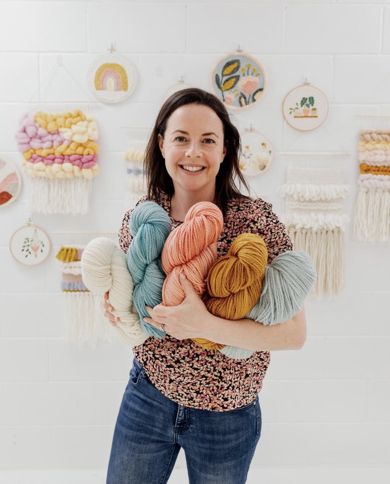 This image shows Julie (the creator of Clever Poppy) holding bundles of coloured punch needle wool.