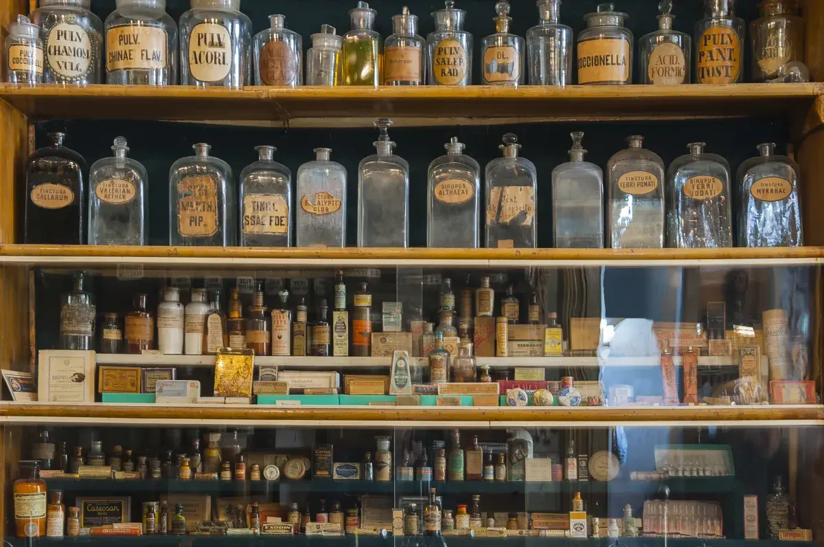 A collection of vintage amber glass apothecary bottles used for historical medicine storage, demonstrating the UV-protective heritage and honey-toned aesthetic that inspired the Prism Amber Collection.