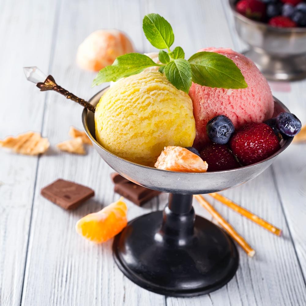 Bowl with ice cream with three different scoops of yellow, red colors and waffle cone, chocolate