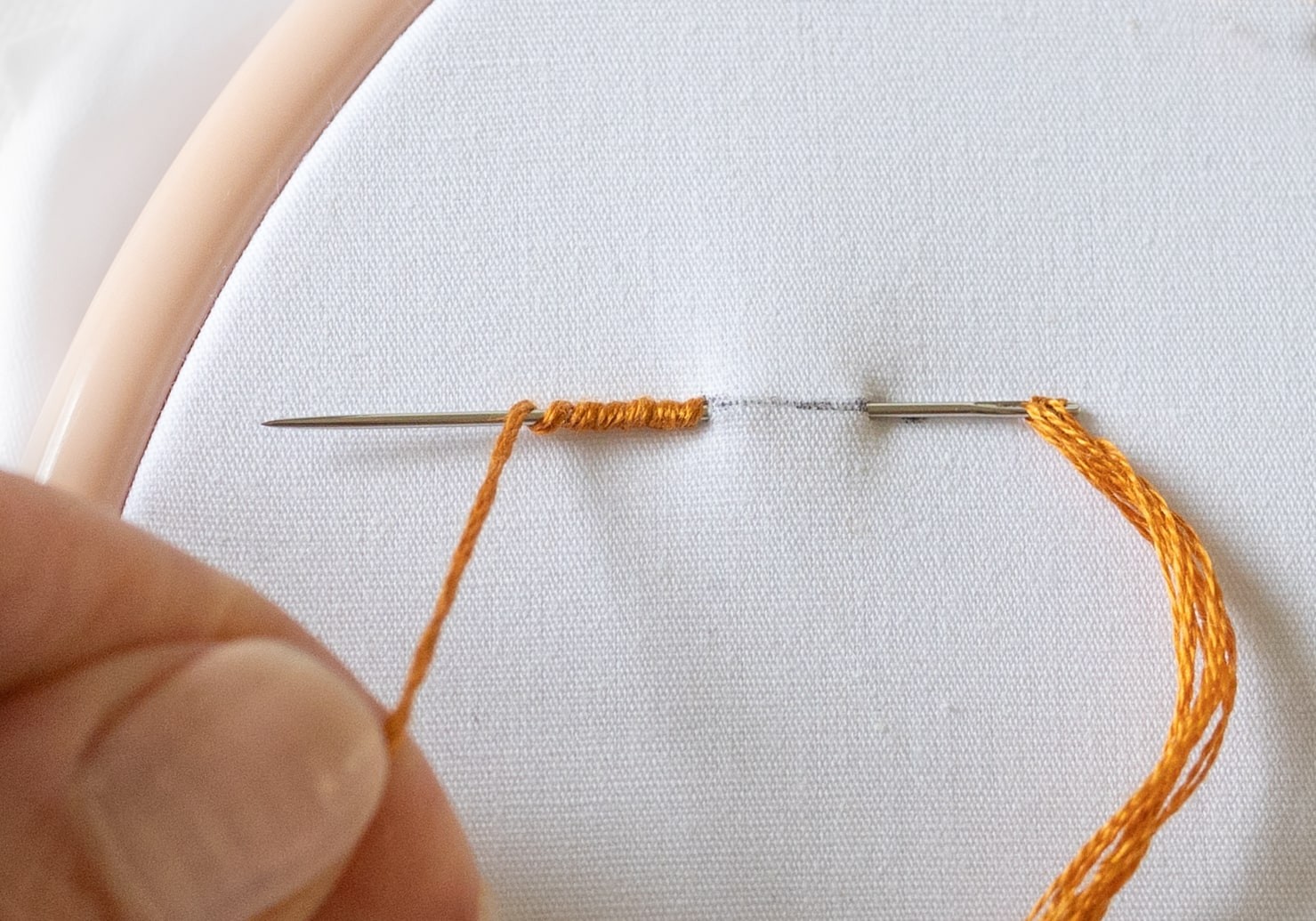 Thread is wrapped around a needle and pulled through cotton.