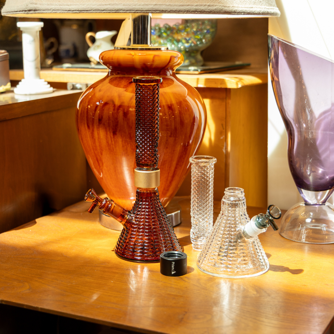 The Jane West x Prism MINI Amber Beaker bong displayed as a home decor centerpiece in a mid-century modern living room, illustrating how premium amber borosilicate glass integrates into stylish, contemporary interior design.