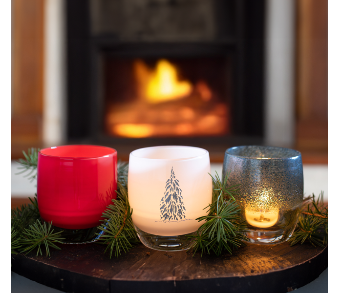 glassybaby transparent glass votive holders in oranges, reds and yellows on wooden bench