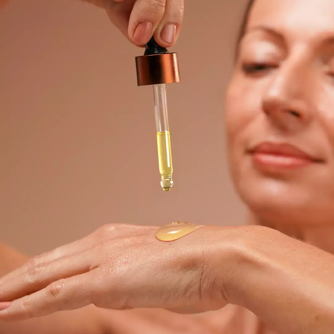 A woman taking a drop of the serum on the back of her palm