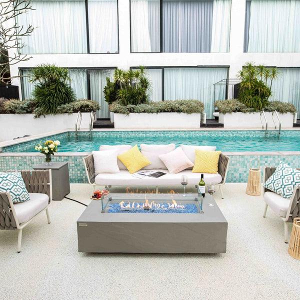 a complete furniture set with fire table beside the pool