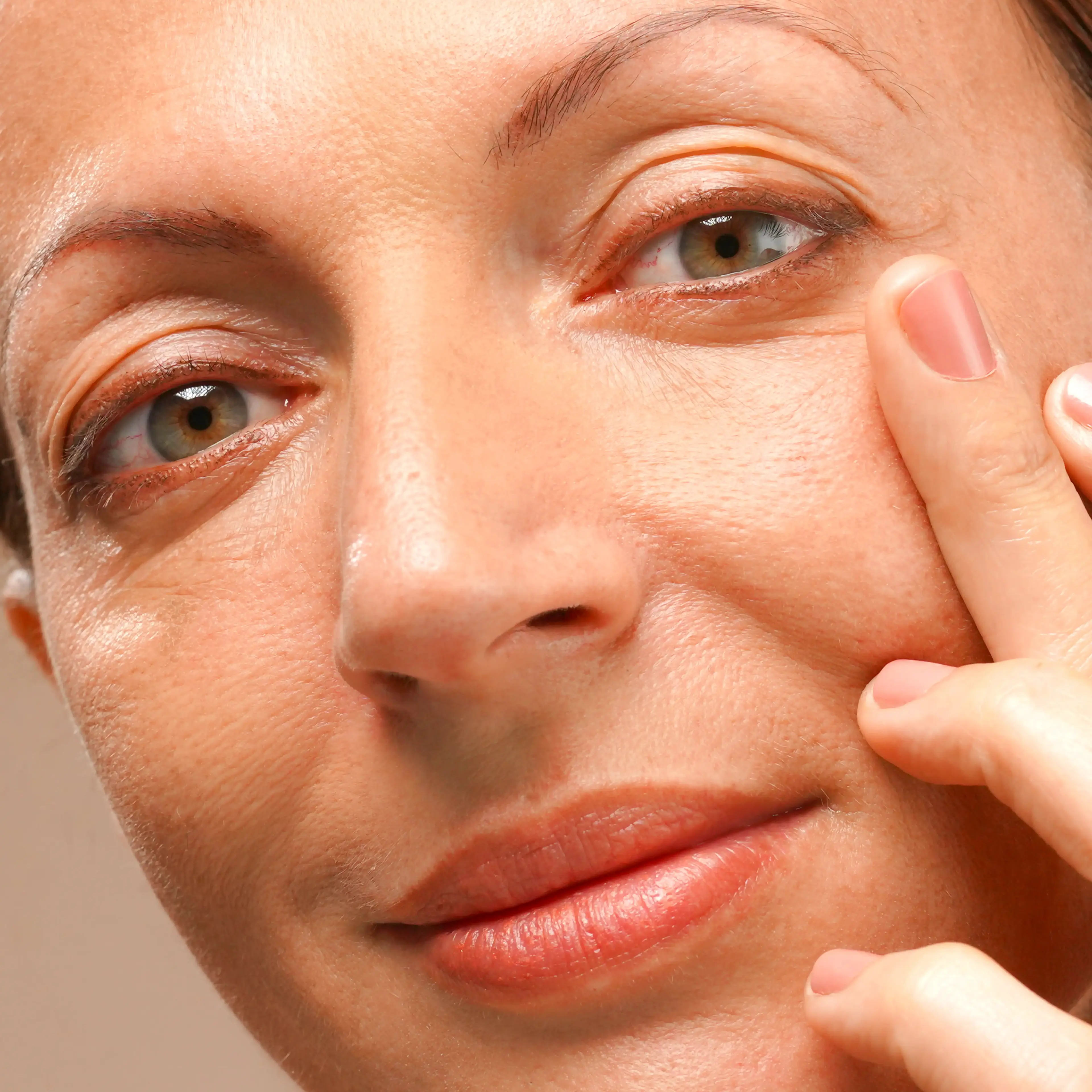 A woman applying serum that hovers to woman holding a touch-me-not flower near her neck