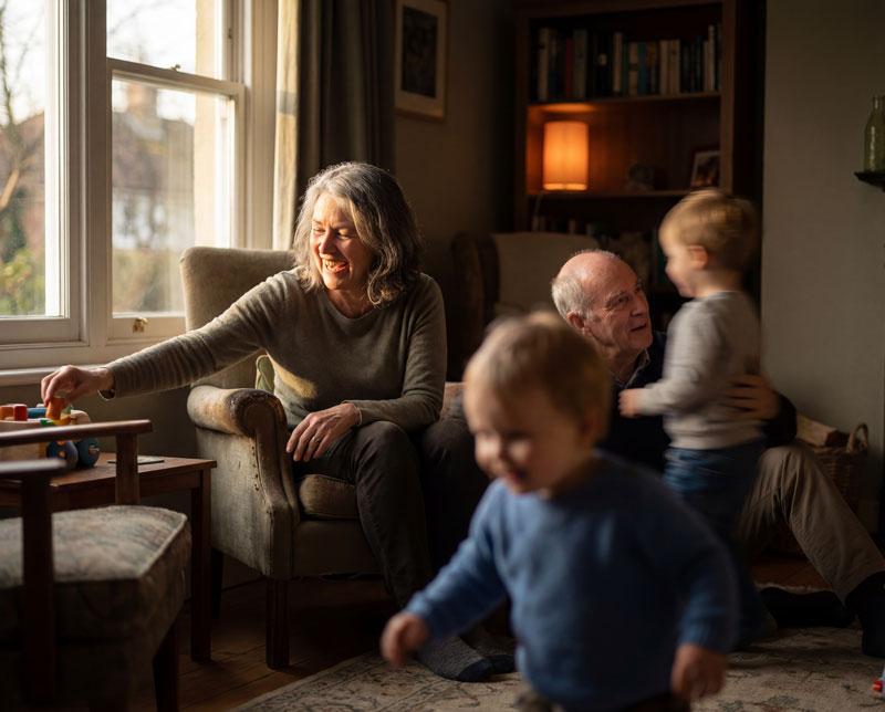 Older woman smiling and playing with grandchildren, feeling happy and engaged at home
