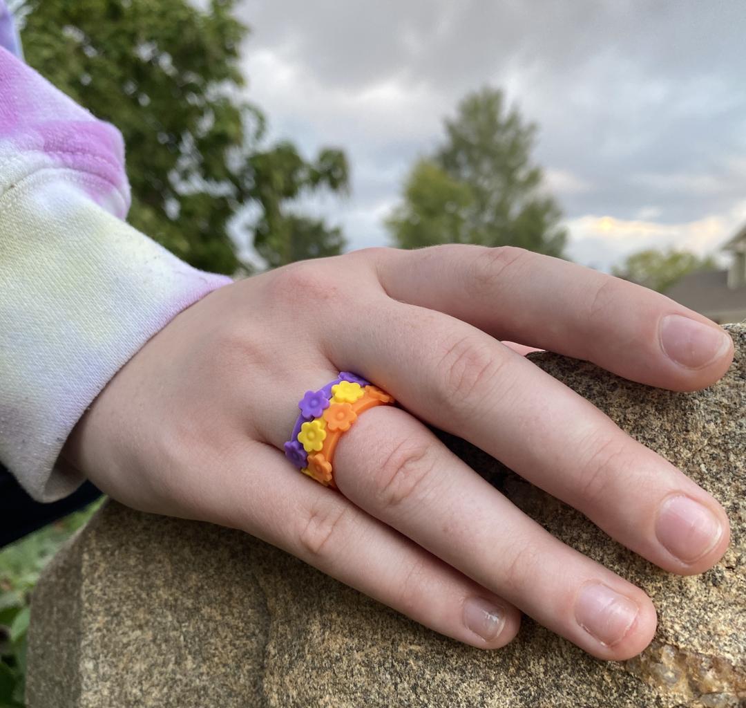 Hand resting on rock while wearing promise garden silicone ring bundle